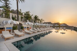 A poolside area with lounge chairs and umbrellas, overlooking a sunset. - San Domenico Palace, Taormina, A Four Seasons Hotel (Taormina)
