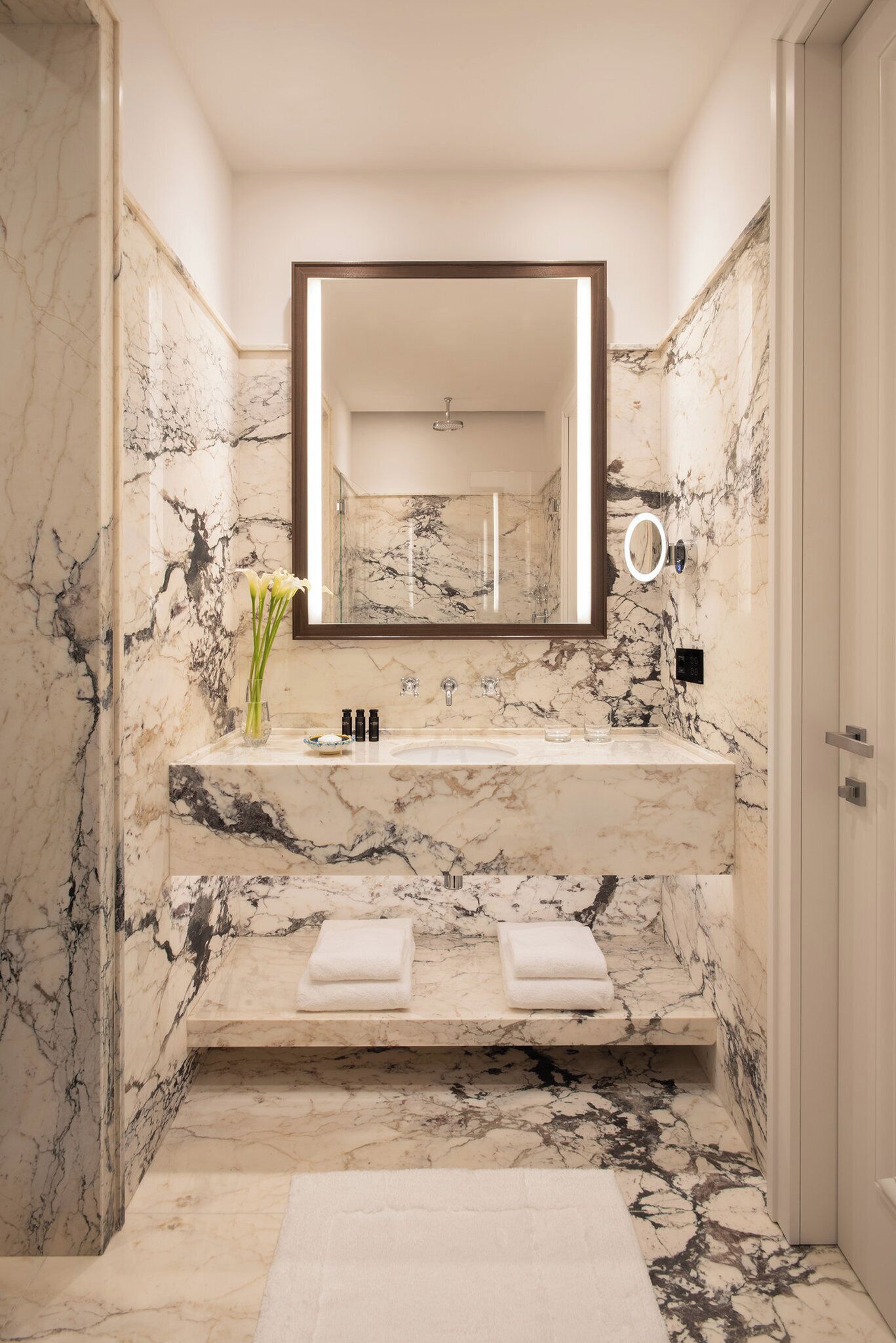 A bathroom with a marble sink, a large mirror, and a towel rack.