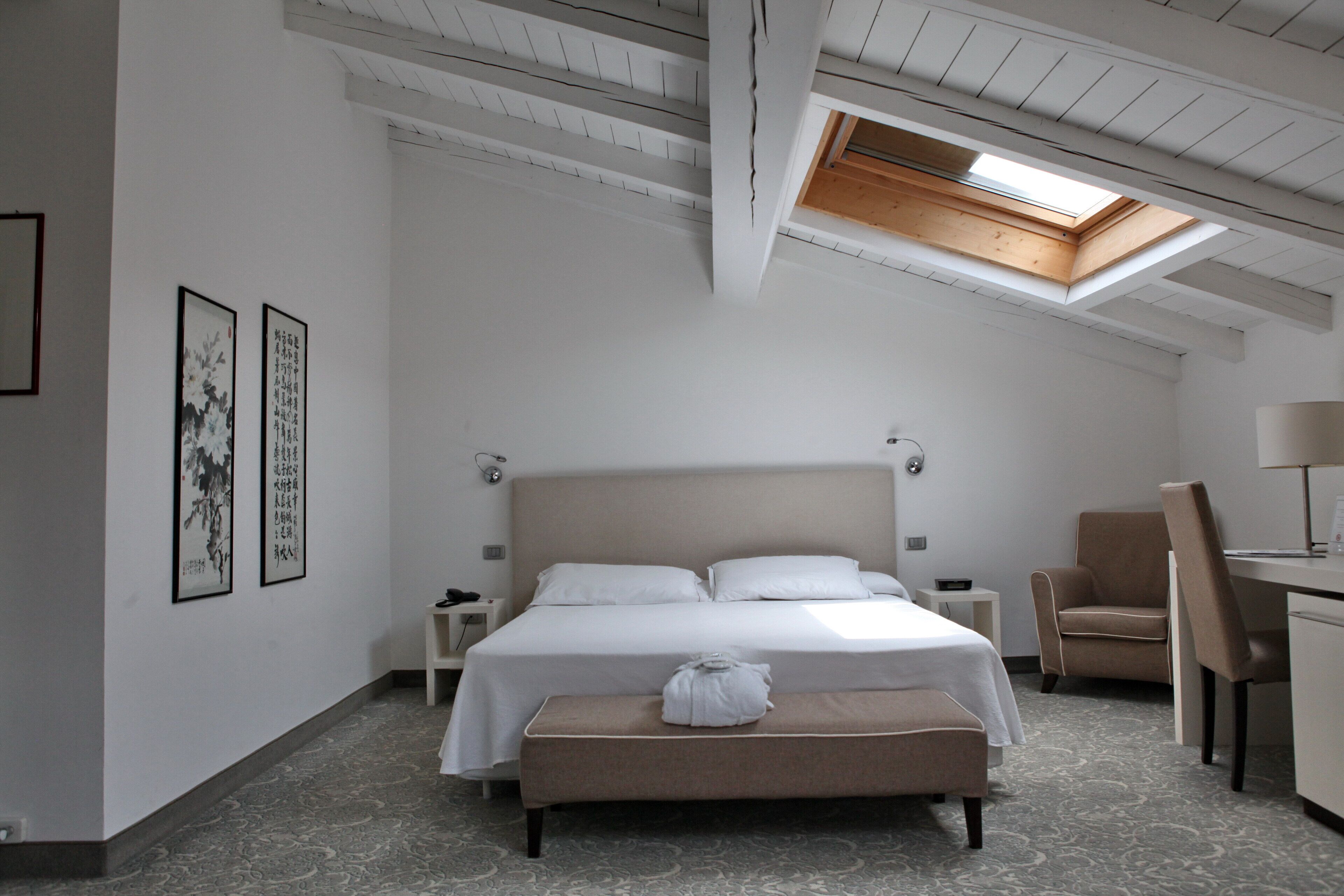 Ein Hotelzimmer mit einem großen Bett, einem Schreibtisch, einem Sessel und einem Dachfenster.