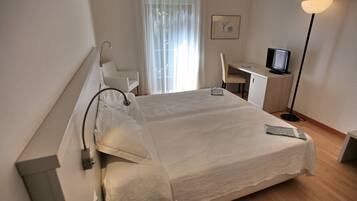 Ein Hotelzimmer mit Bett, Schreibtisch, Stuhl, Fernseher und Lampe.