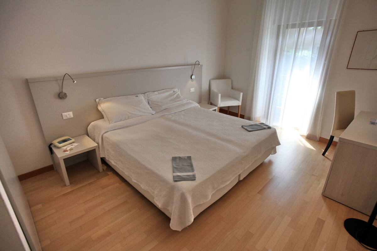 Une chambre d’hôtel avec un grand lit, des tables de chevet, une chaise et un bureau.