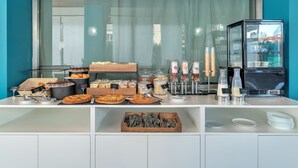 Un bufé de desayuno con diferentes alimentos, una cafetera y un refrigerador.