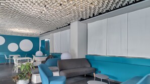 Un interior moderno con techo geométrico, paredes color turquesa y mobiliario contemporáneo.