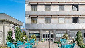 Un edificio moderno con un patio que ofrece asientos al aire libre y abundante vegetación.