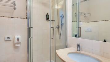 A modern bathroom with a glass-enclosed shower, a sink, and a toilet.