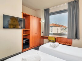 A hotel room with a bed, a desk, a wardrobe, and a TV.