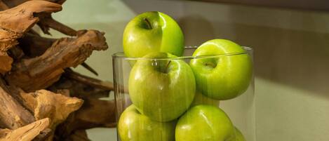 Een presentatie van groene appels in een glazen pot, omringd door potten met noten en zaden en voedingsinformatie labels.
