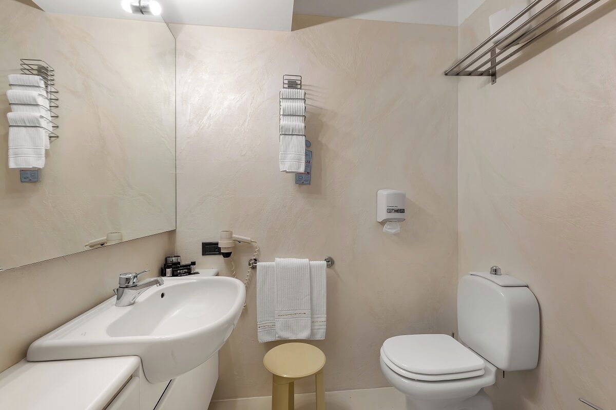 A modern bathroom with a sink, toilet, and towel rack.