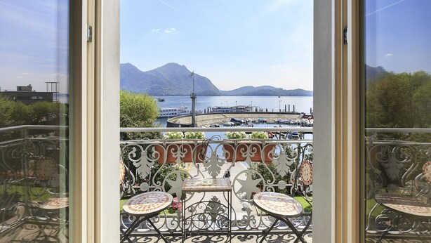 A balcony with a view of a lake, boats, and mountains. - Hotel Ancora (Verbania)