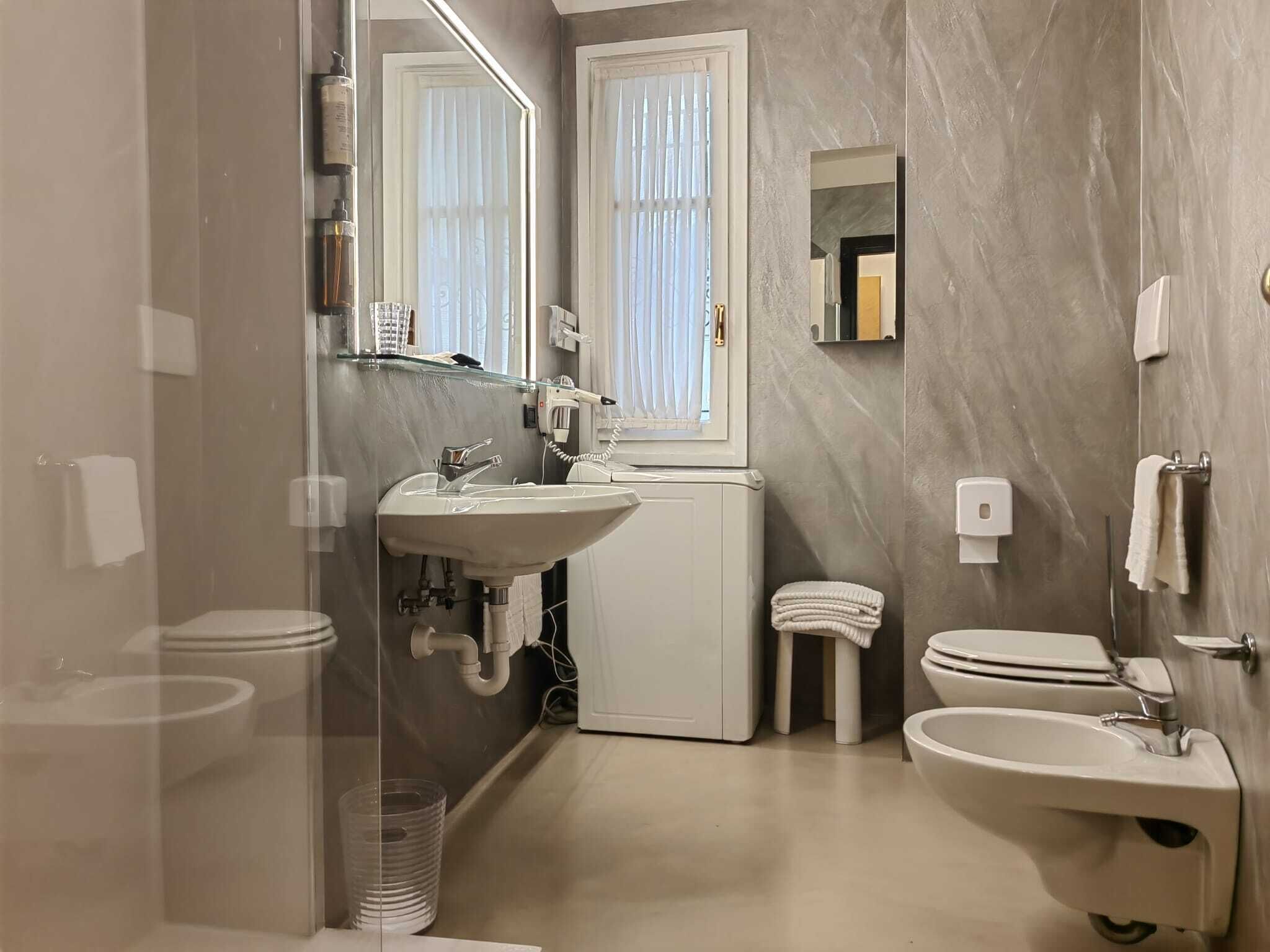 A modern bathroom with a large mirror, a sink, a toilet, and a bidet.