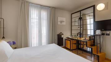 A hotel room with a large bed, a desk with a chair, a television, and a mirror.