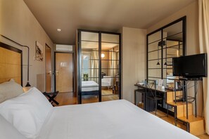 Una habitación de hotel con una cama grande, un escritorio con televisor y un espejo.