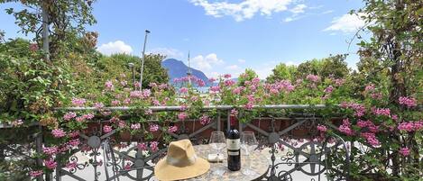 Una terraza con una mesa, sillas, una botella de vino y un sombrero.