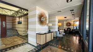 A hotel lobby with a staircase, a reception desk, and a seating area. - Hotel Ancora (Verbania)