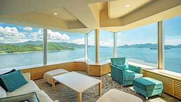 Una habitación moderna con ventanas amplias, un sofá, una mesa y dos sillones.