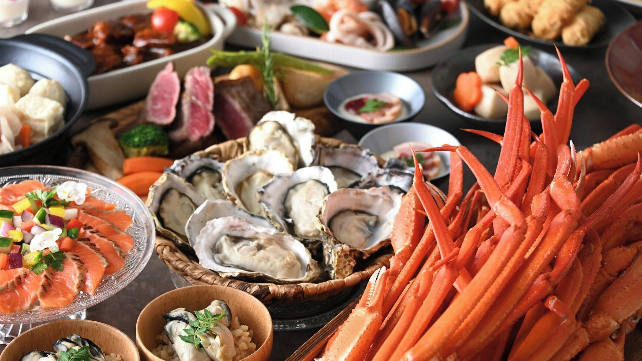 A variety of seafood dishes including oysters, crab legs, and salmon.