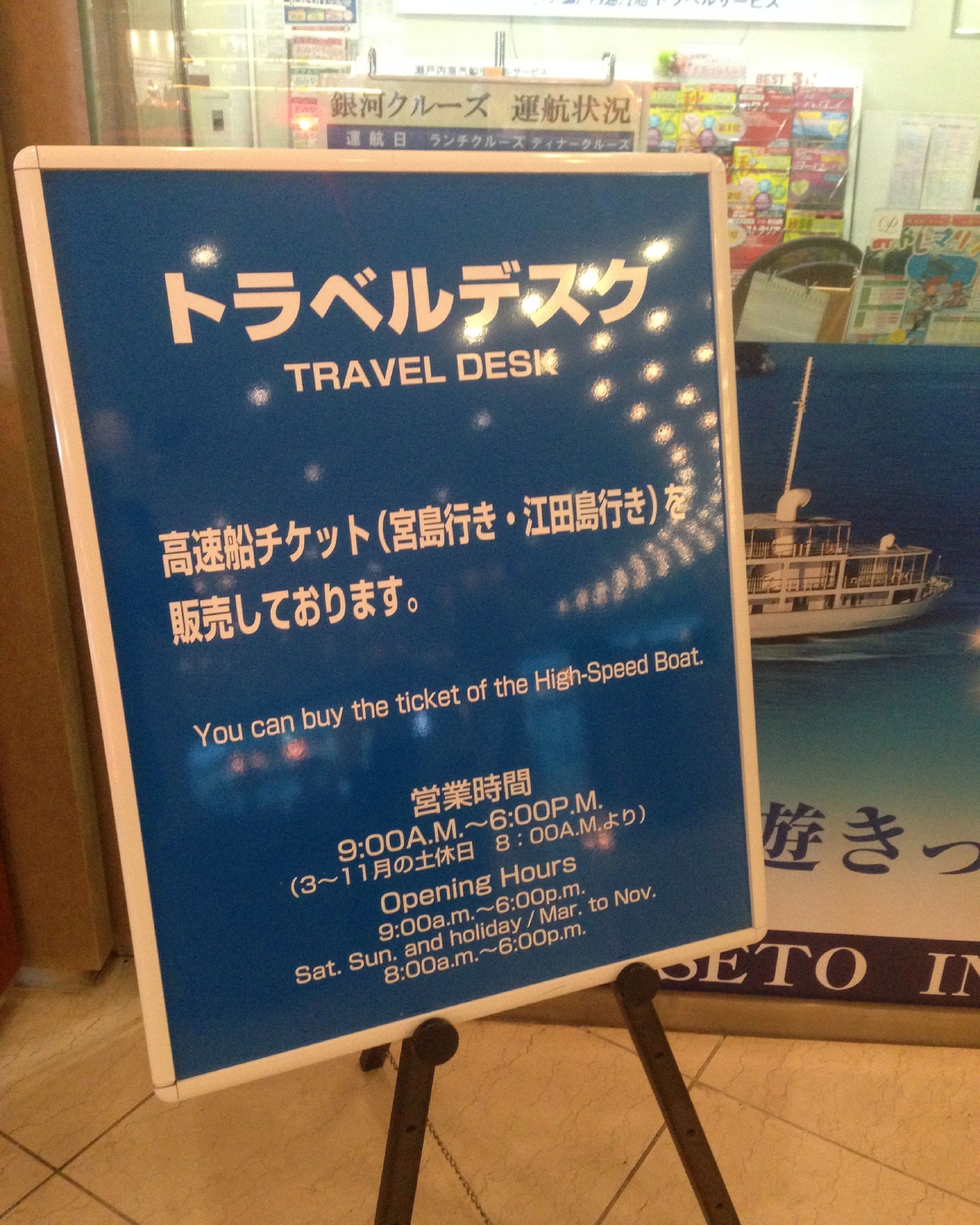 A travel desk with a sign in Japanese and English, indicating the sale of high-speed boat tickets.