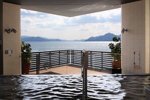A spa area with a view of a lake and mountains, featuring a wooden deck and tiled walls. - Grand Prince Hotel Hiroshima (Hiroshima)