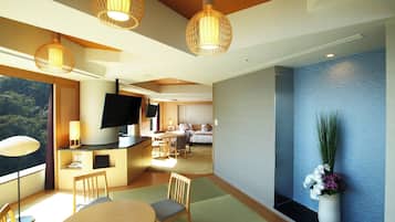 Una camera d'hotel moderna con zona pranzo, TV e un'ampia finestra vista esterna.
