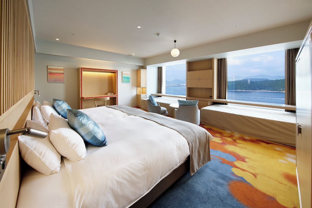 Habitación de hotel con una cama grande, un escritorio y vista al mar.