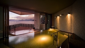 Un interior moderno con vista al mar, barandilla de vidrio y pared de azulejos.