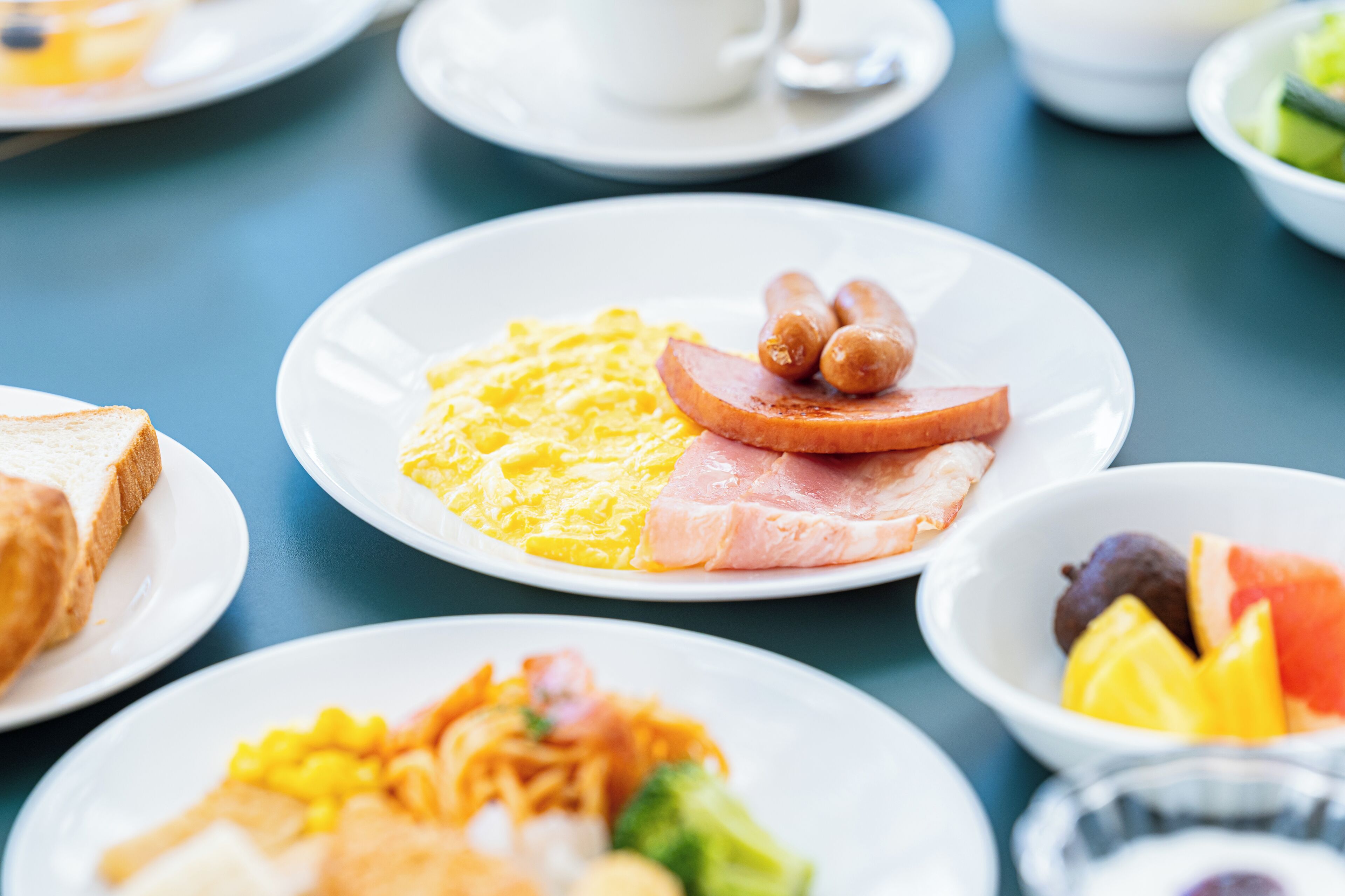 Une table mise pour le petit-déjeuner avec des assiettes contenant des œufs, du jambon et des toasts.