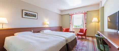 A hotel room with two beds, a desk, a chair, a television, and a window with curtains.