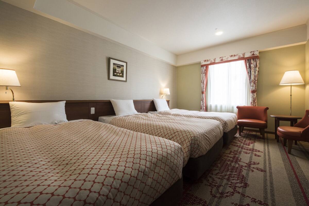 Ein Hotelzimmer mit zwei Betten, einem Schreibtisch und einem Stuhl.