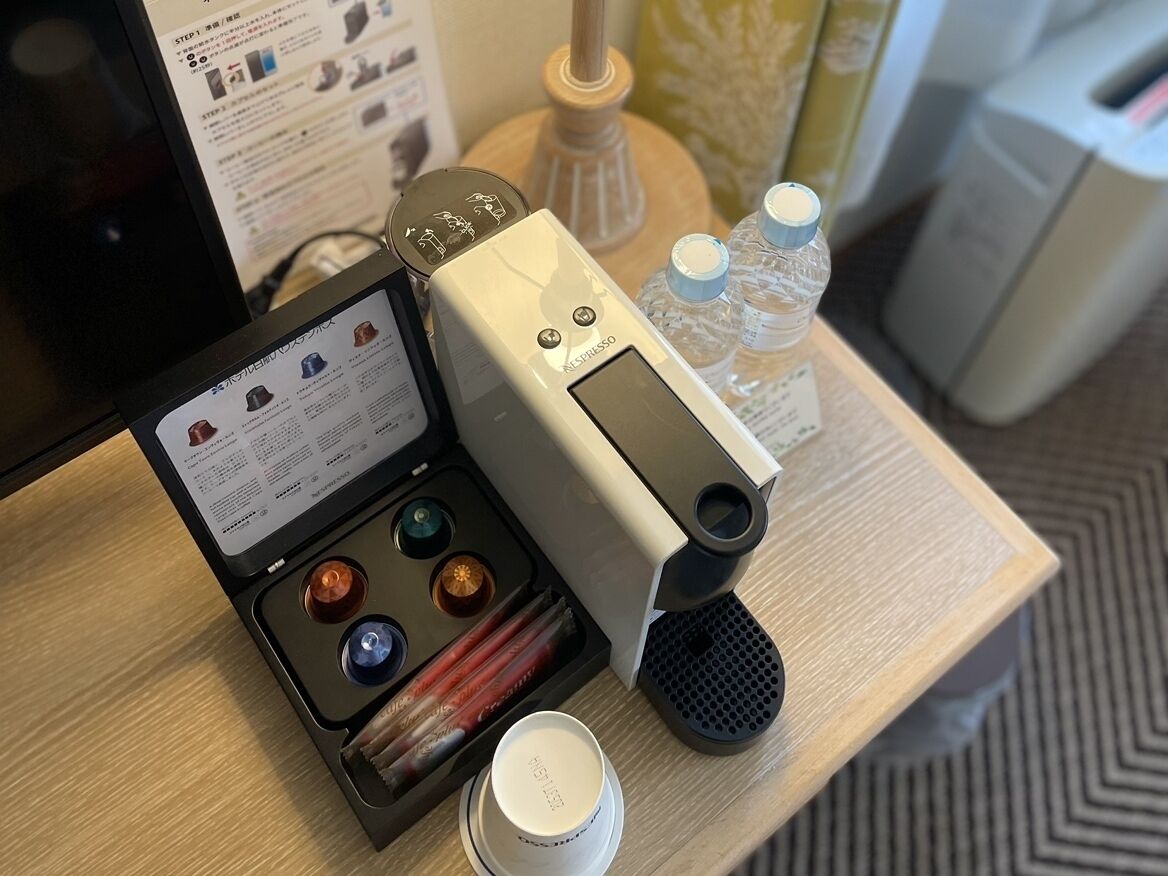 A coffee machine with a digital display, a coffee pod holder, and a water bottle on a wooden table.