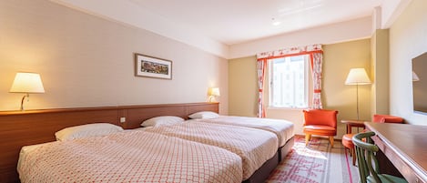 Habitación de hotel con una cama grande, dos mesitas de noche, un escritorio con silla y una ventana con cortinas.