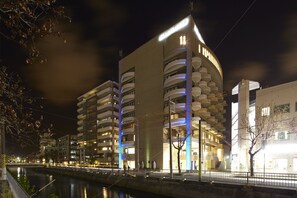 Un edificio moderno con varios balcones y un río al frente.
