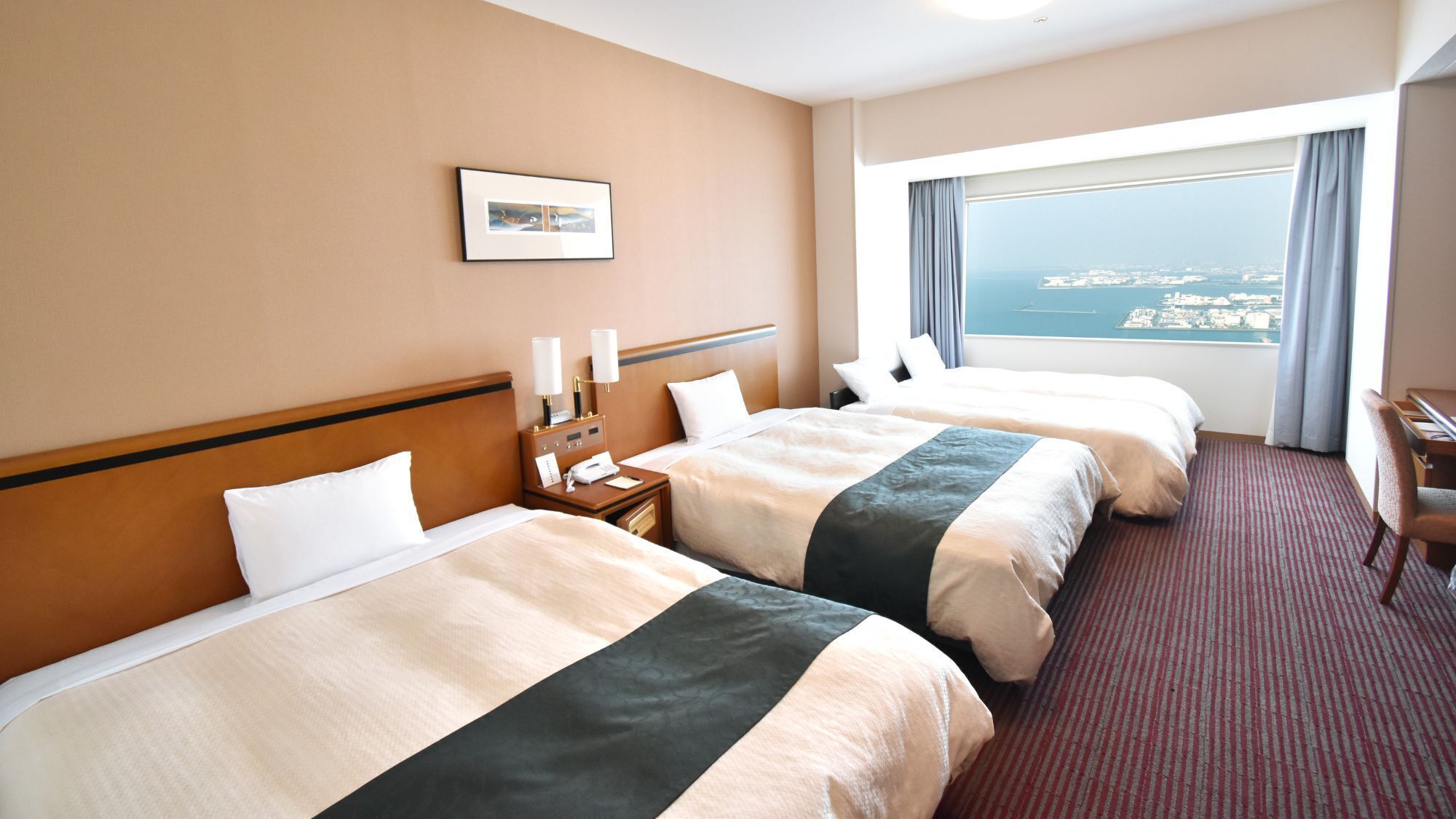 Une chambre d’hôtel avec deux lits, un bureau, une chaise, une table de chevet avec une lampe, un téléphone et une fenêtre donnant sur un paysage agréable.