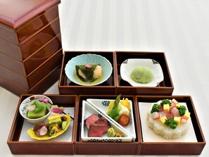 A traditional Japanese meal set in a wooden box with compartments containing various dishes. - Star Gate Hotel Kansai Airport (Izumisano)