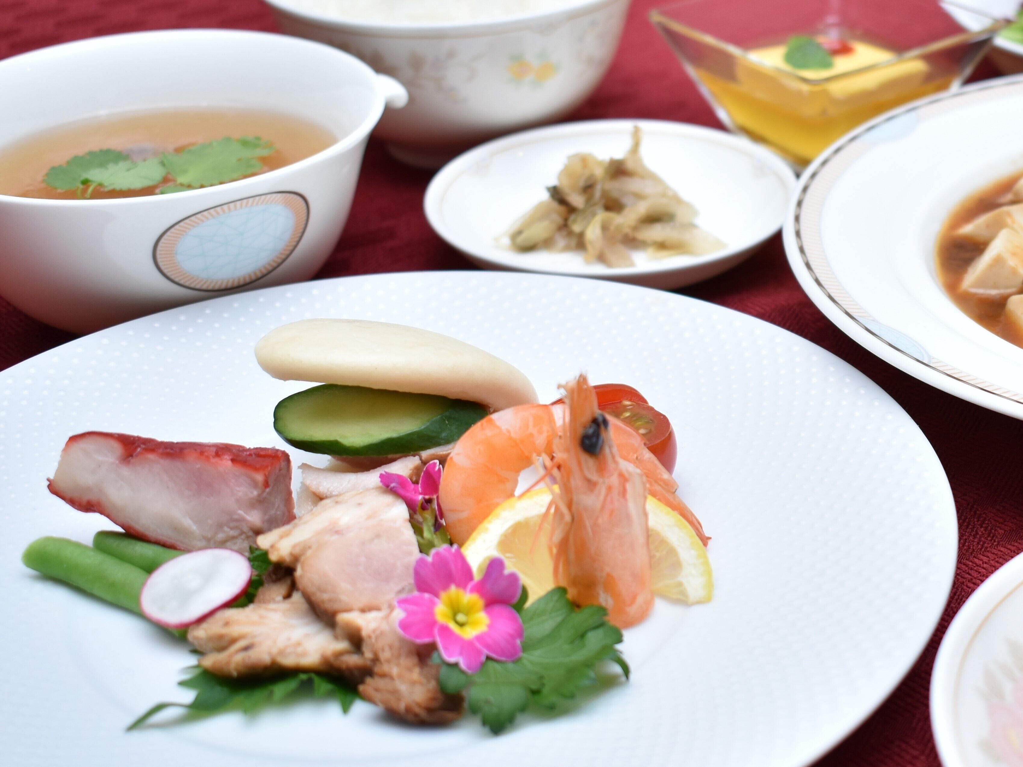 A table with various dishes including seafood, vegetables, and a bowl of soup.