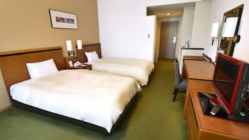 Quarto de hotel com duas camas, uma escrivaninha com computador, uma cadeira e um espelho.