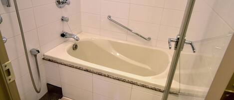 A modern bathroom with a freestanding bathtub, a glass shower enclosure, and a toilet.