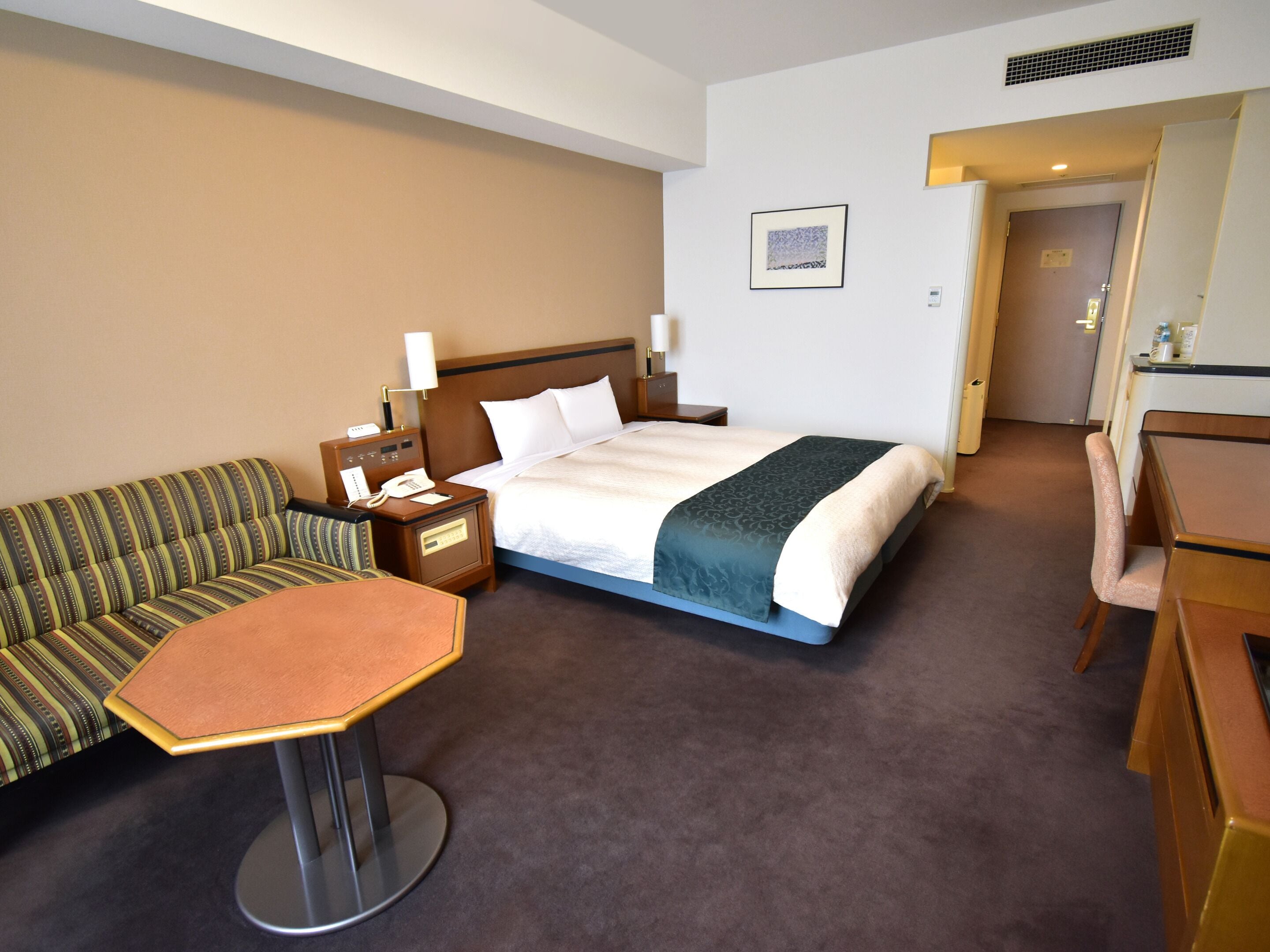 Ein Hotelzimmer mit Bett, einer Couch, einem kleinen Tisch und einem Schreibtisch.