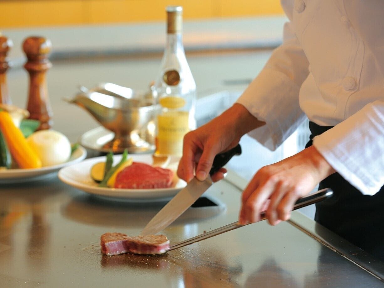Un chef cortando carne en una encimera de cocina.