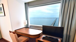 A hotel room with a large window, a desk with a flat-screen TV, a chair, and a lamp. - Star Gate Hotel Kansai Airport (Izumisano)