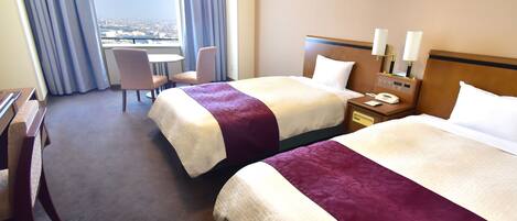 A hotel room with two beds, a desk, a chair, a nightstand with a phone, and a window with curtains.
