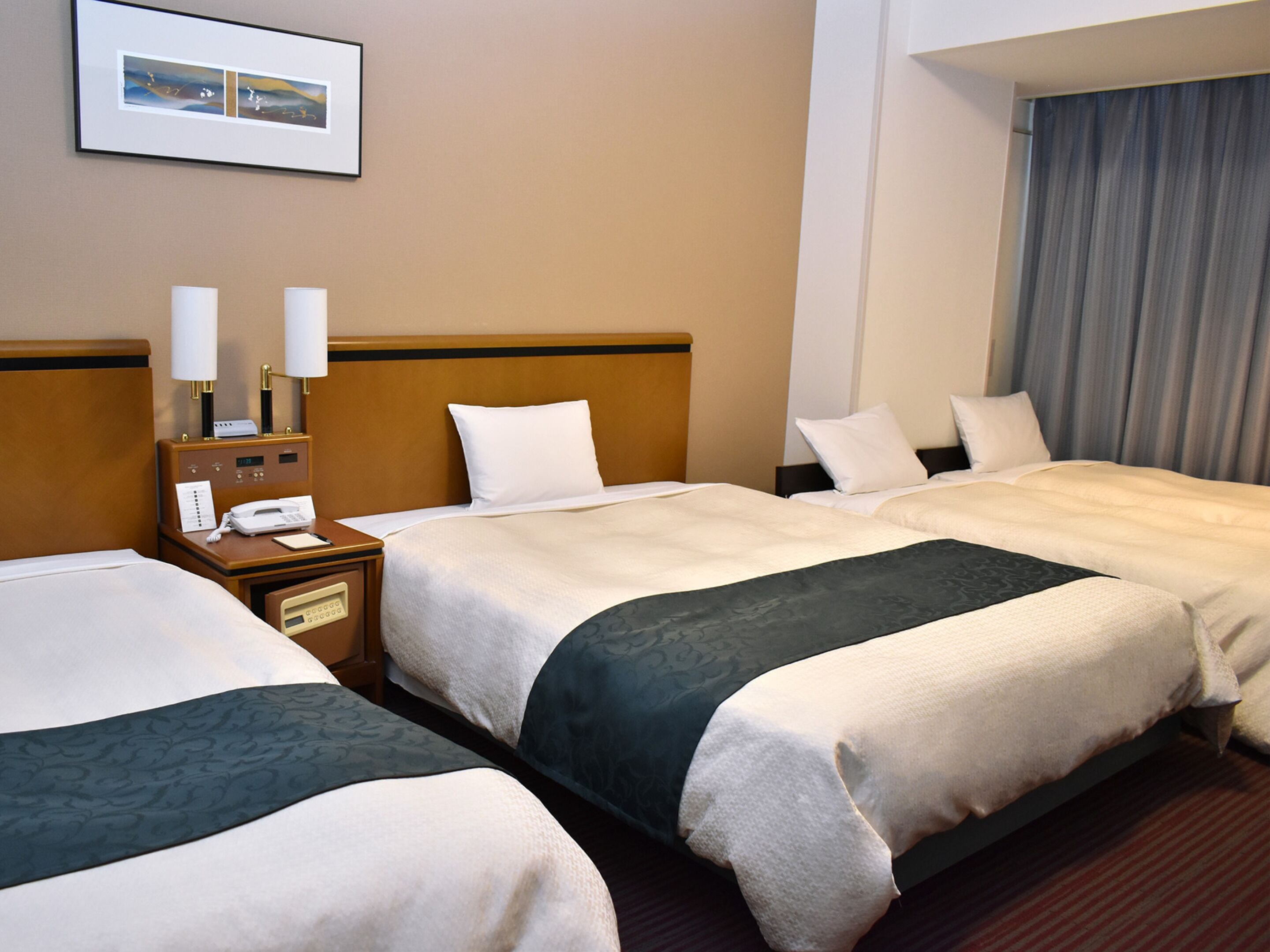 Ein Hotelzimmer mit zwei Betten, einem Nachttisch mit Telefon und einer Wandlampe.
