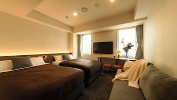 Een hotelkamer met twee bedden, een bank, een televisie en een bureau met een vaas.