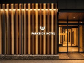 A hotel entrance with vertical wooden slats and a glowing sign reading 'PARKSIDE HOTEL'. - Hotel Sho Sapporo (ParkSide Hotel) (Sapporo)