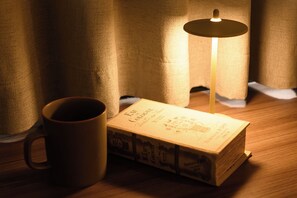 A candle on a table with a book and a mug. - Hotel Sho Sapporo (ParkSide Hotel) (Sapporo)