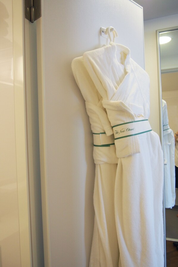 A white robe hanging on a wall with a green ribbon and the text "The New Otani".