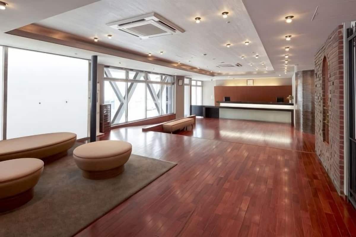 Een ruime lobby met houten vloeren, een receptiebalie en een zithoek met banken.