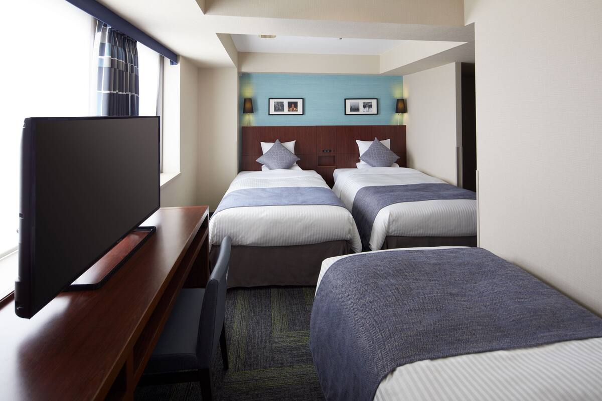 Een hotelkamer met twee bedden, een bureau en een televisie.