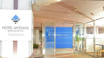 La entrada al HOTEL MYSTAYS Yokohama, con un moderno fachada de vidrio y un cartel.
