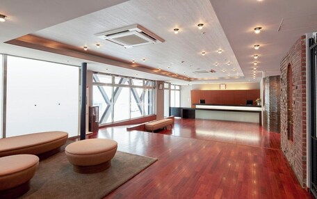 A spacious lobby with a reception desk, seating area, and large windows.