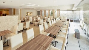 A modern conference room with long tables and white chairs, large windows, and a stone accent wall. - Hotel MyStays Yokohama (Yokohama)